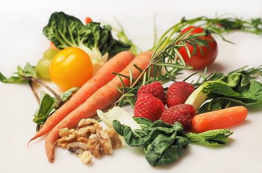 Das Bild zeigt Gemüse wie Karotten, Tomaten, Kohl und Früchte wie Himbeeren, Nüsse.