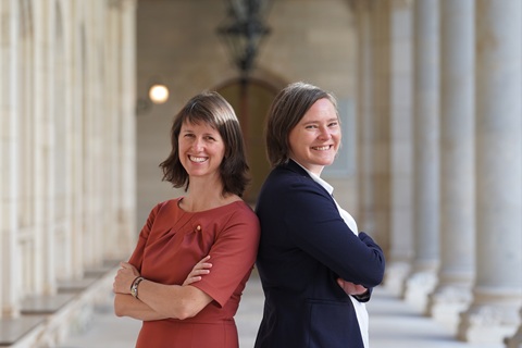 Auf dem Bild stehen die Gemeinderätin Stefanie Vasold (rechts) und ihre Stellvertreterin Gemeinderätin Astrid Rompolt (links) Rücken an Rücken mit verschränkten Armen. Sie lächeln in in die Kamera.