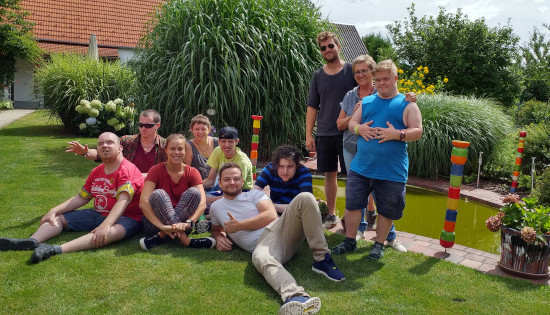 Gruppenfoto mit Betreuern und Klienten, die im Gras sitzen