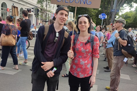 Auf dem Bild ist unsere neue Assistentin gemeinsam mit unserem Kunden Mathis zu sehen. Beide sind sommerlich gekleidet. Sie stehen auf der Straße und halten ein Schild, weil sie auf einer Demonstration für inklusive Bildung sind. Auf dem Schild steht „Recht auf inklusive Bildung“.